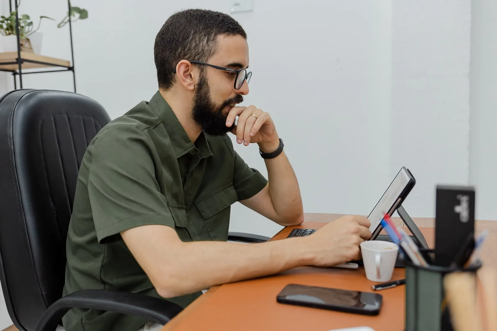 Thiago Souza no consultório, lendo em um tablet à mesa de trabalho